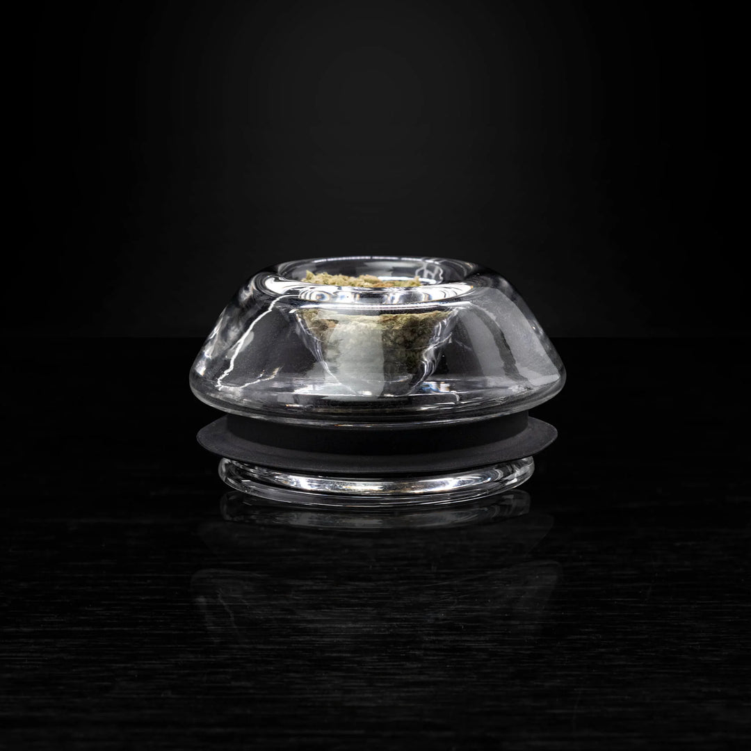 Puffco Proxy Flower Bowl on black reflective surface, showcasing its sleek glass design for dry herb use with Puffco vaporizers.