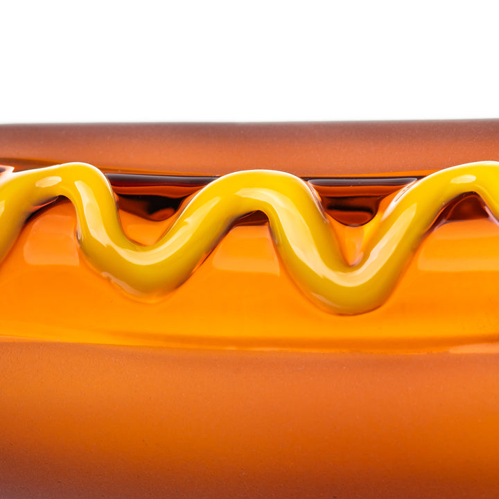 The BigFun! Glizzy Hand Pipe photographed to highlight the yellow mustard zigzag across the full-color glass hot dog