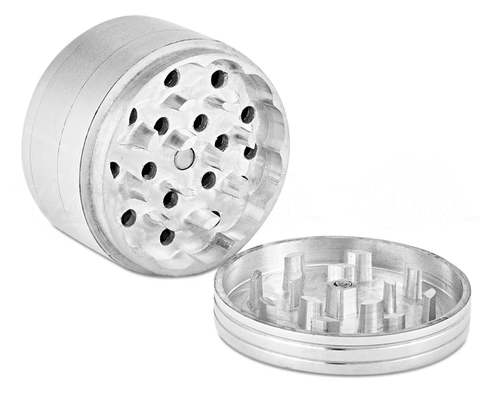 Aluminum grinder on its side with top open showing sharp teeth and holes