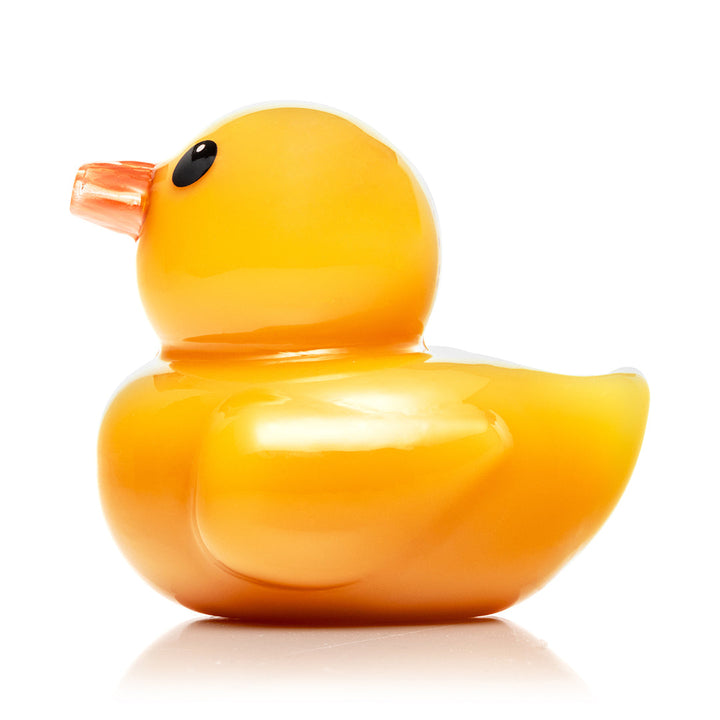 Hemper Ducky Hand Pipe seen from the left, showing the yellow glass duck body, orange beak mouthpiece and the carb hole on the left side