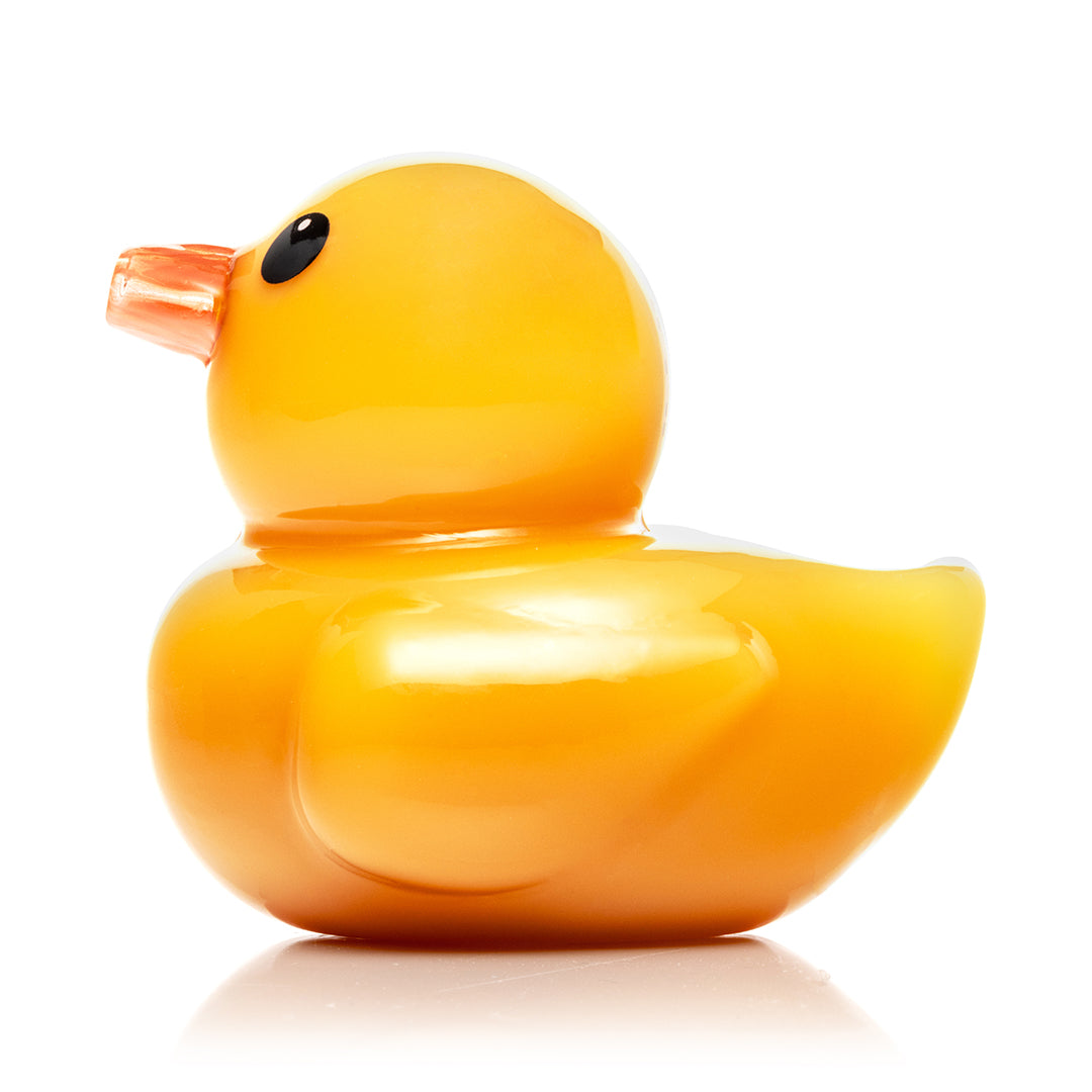 Hemper Ducky Hand Pipe seen from the left, showing the yellow glass duck body, orange beak mouthpiece and the carb hole on the left side