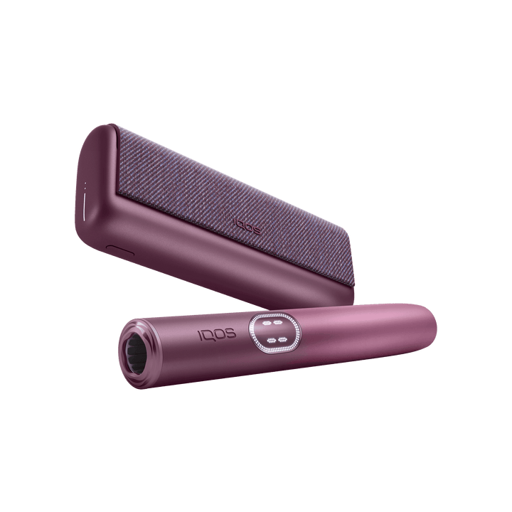 IQOS ILUMA i PRIME Garnet Red holder in front of the pocket charger, low angle showing the mouth end