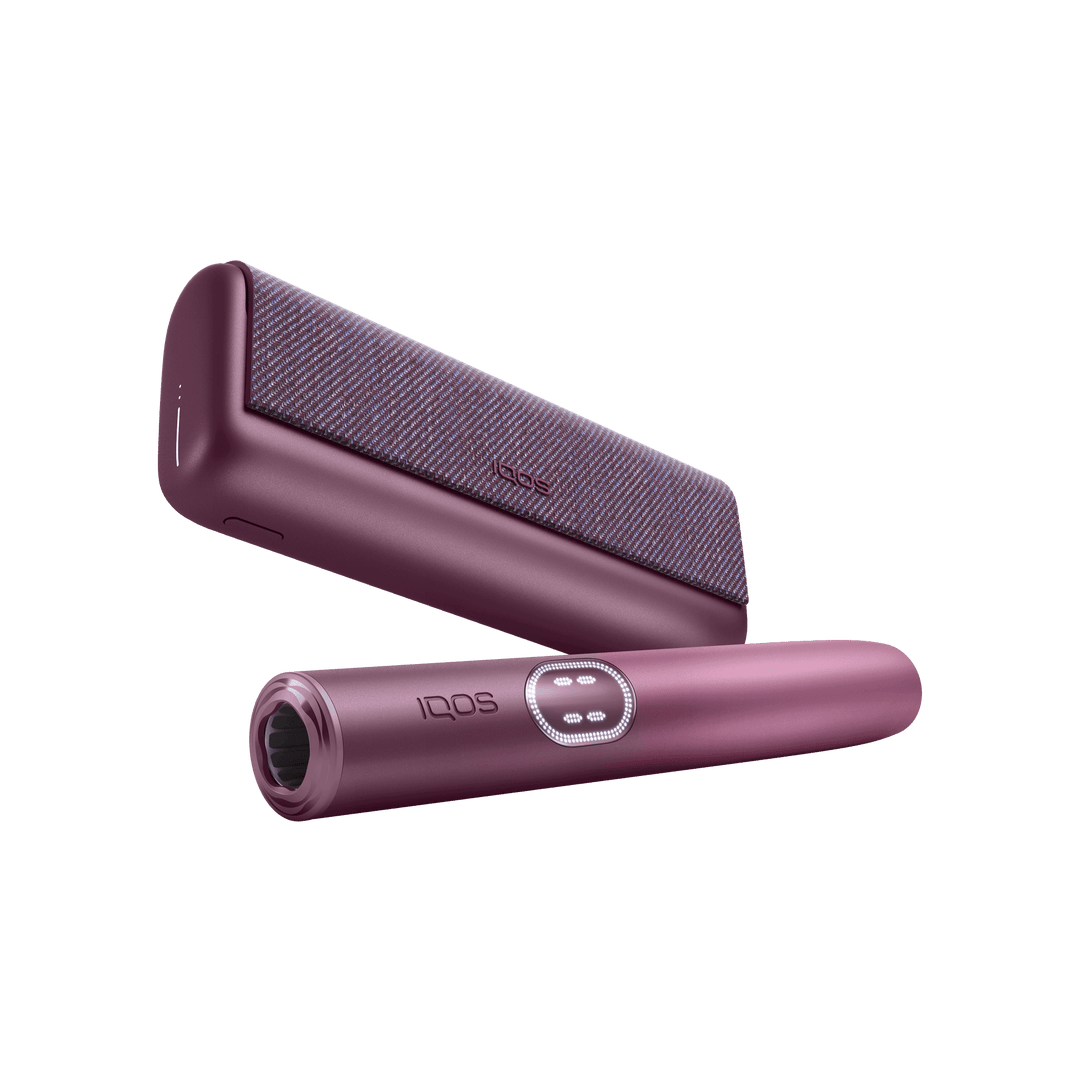 IQOS ILUMA i PRIME Garnet Red holder in front of the pocket charger, low angle showing the mouth end