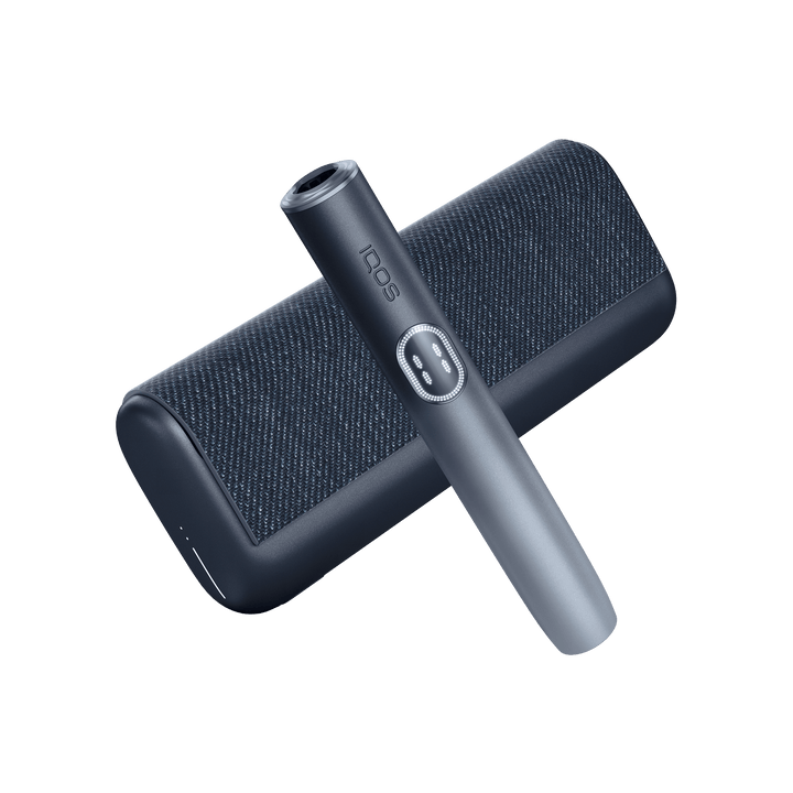 IQOS ILUMA i PRIME Midnight Black holder laid diagonally across the closed textured pocket charger