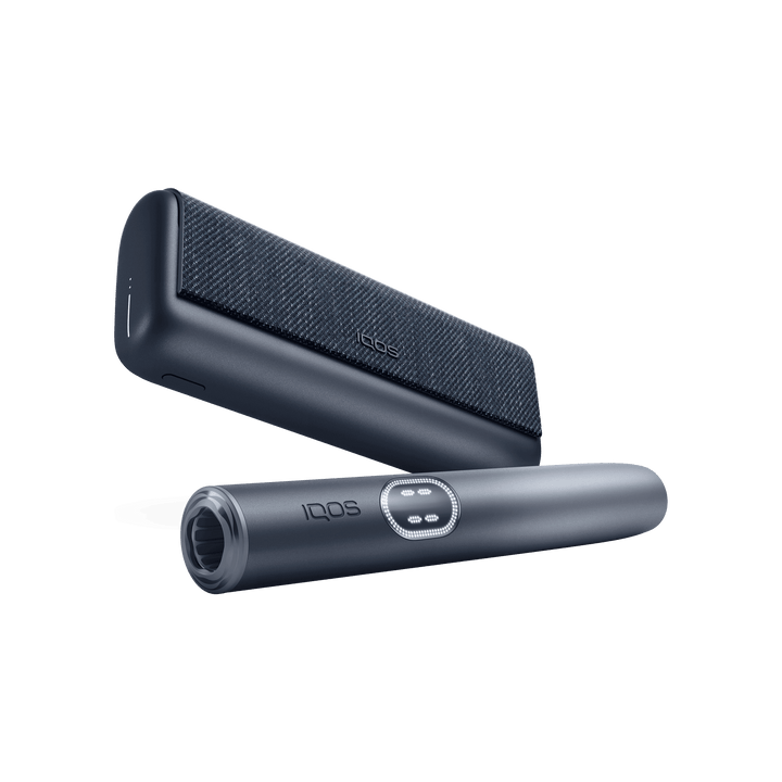 IQOS ILUMA i PRIME Midnight Black holder in front of the pocket charger, low angle showing the mouth end