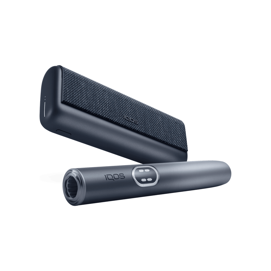 IQOS ILUMA i PRIME Midnight Black holder in front of the pocket charger, low angle showing the mouth end