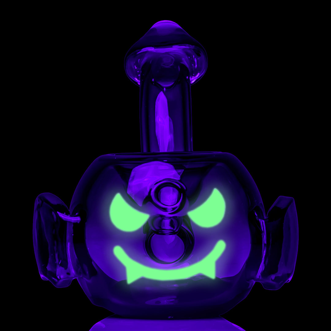 MJ Arsenal Bud-Sucker Hand Pipe under black light, front view of the glowing green face between the wings
