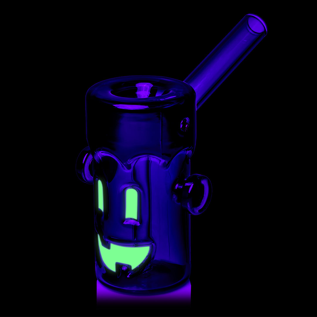 MJ Arsenal Frankenbubbler under black light, three-quarter view with the mouthpiece to the right and the face glowing