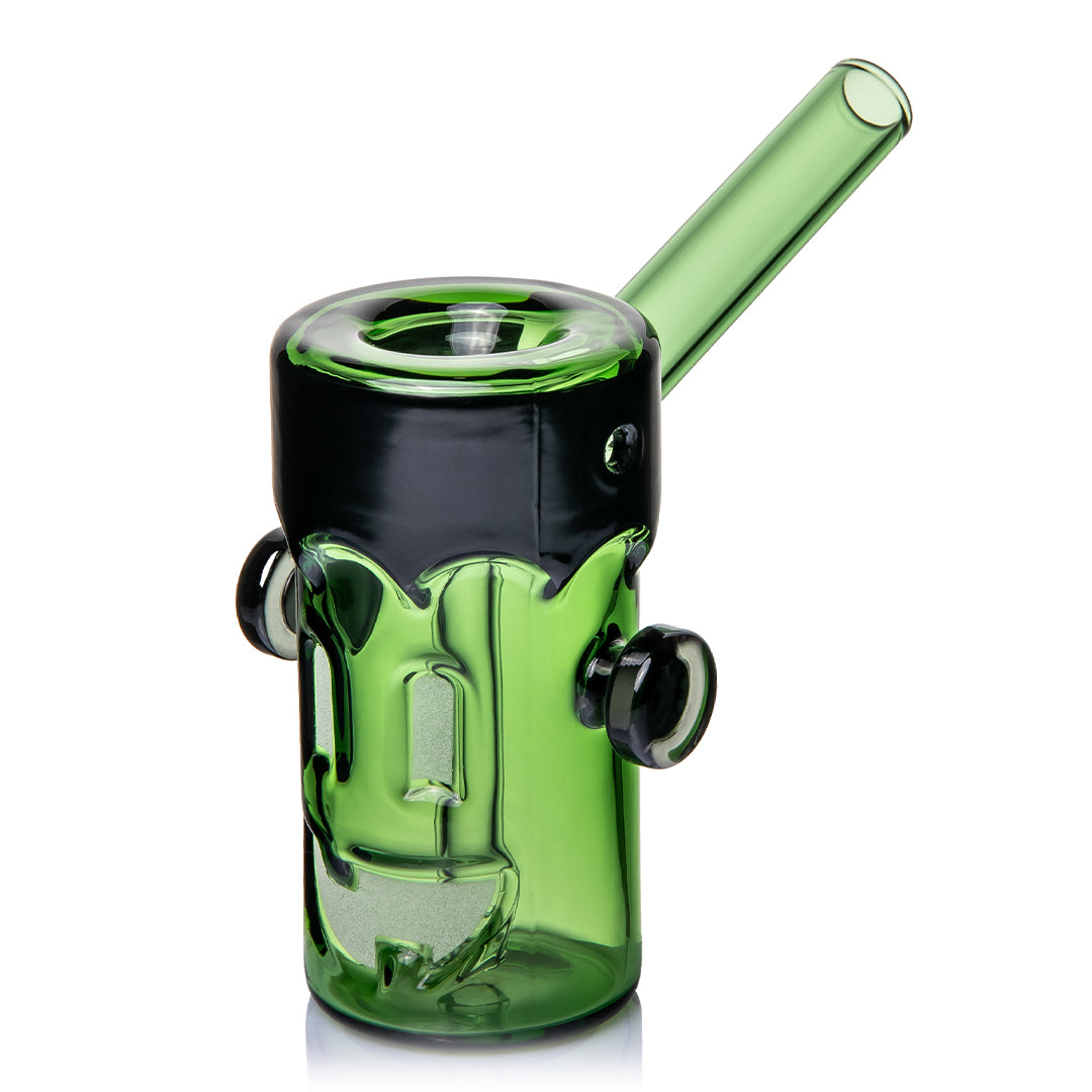 MJ Arsenal Frankenbubbler, a 4.5 inch green borosilicate hand bubbler shaped as a monster head, with a black flat top that drips down the glass, black bolt knobs on each side, the bowl recessed into the top and a green mouthpiece angled up from the back
