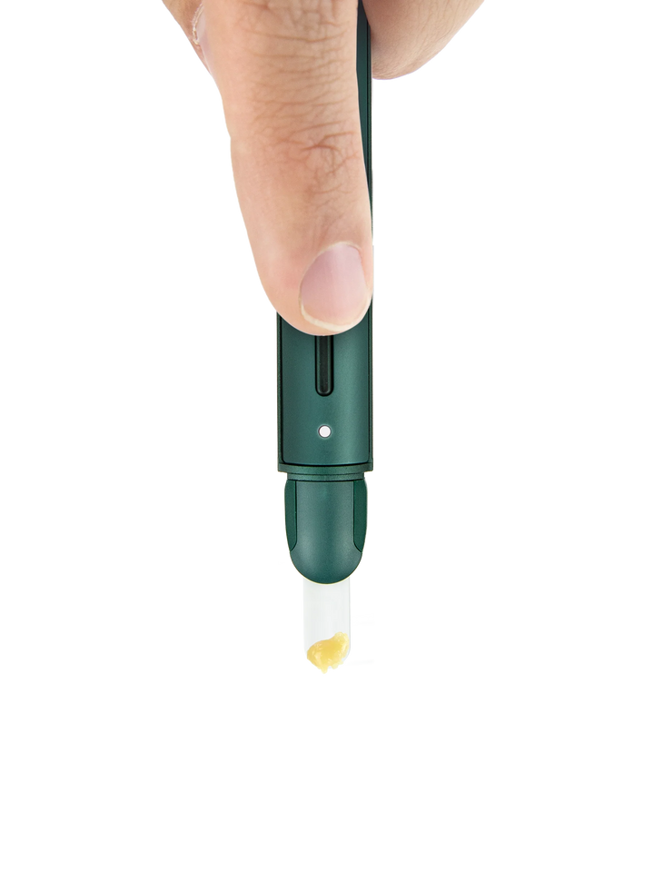 Puffco Hot Knife (New Version) in Pine held in the hand, showing the slim pen-sized scale of the heated loading tool